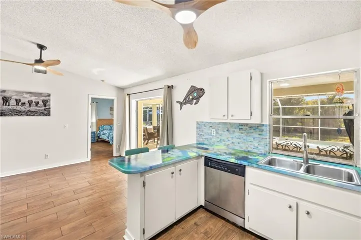 Kitchen featuring dishwasher, a sink, a peninsula, a textured ceiling, and ceiling fan