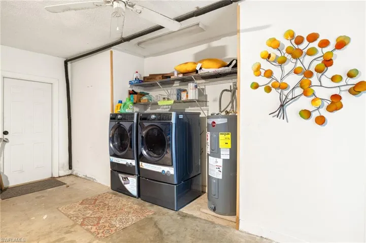 Clothes washing area featuring separate washer and dryer, electric water heater, laundry area, and a ceiling fan