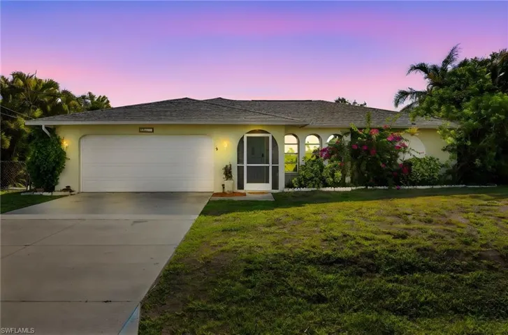 Ranch-style home featuring an attached garage, driveway, a yard, and stucco siding