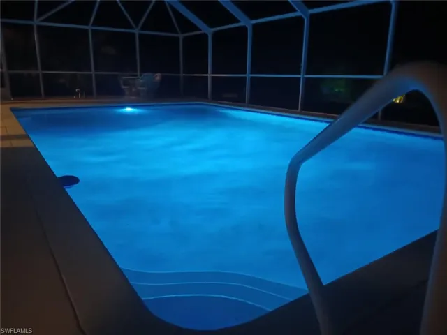 Pool featuring a water slide, glass enclosure, and a patio
