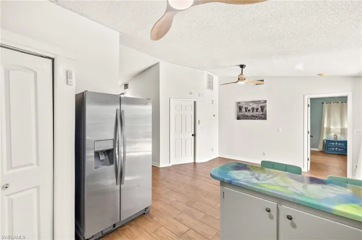 Kitchen featuring ceiling fan, stainless steel refrigerator with ice dispenser, a textured ceiling, and light wood-style flooring