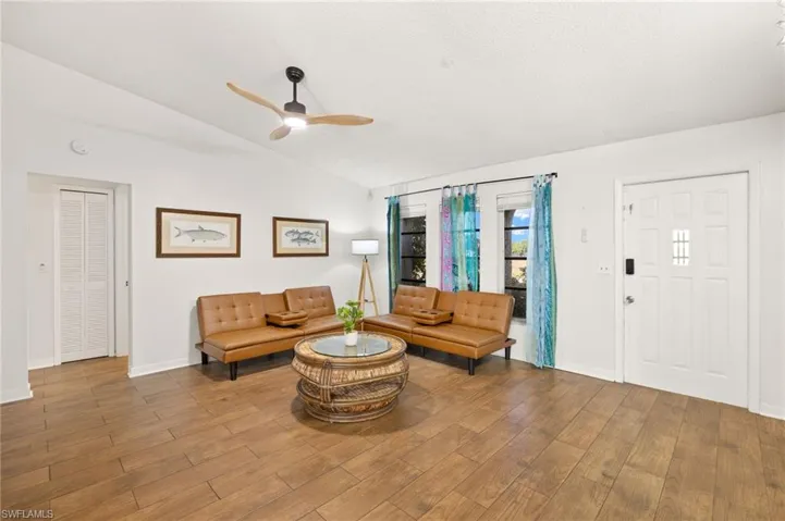 Living area with lofted ceiling, wood finished floors, baseboards, and ceiling fan