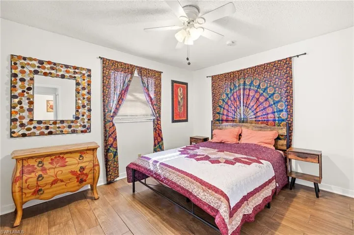 Bedroom with wood finished floors, a textured ceiling, a ceiling fan, and baseboards