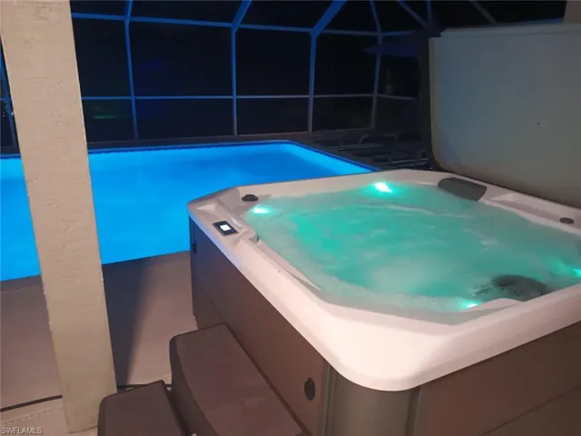 View of pool with a pool, glass enclosure, and a hot tub