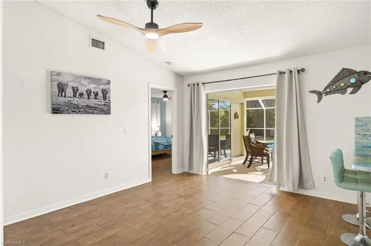 Spare room with wood finished floors, a textured ceiling, ceiling fan, and visible vents