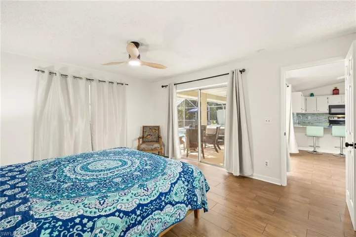 Bedroom featuring baseboards, wood finished floors, a textured ceiling, and access to exterior