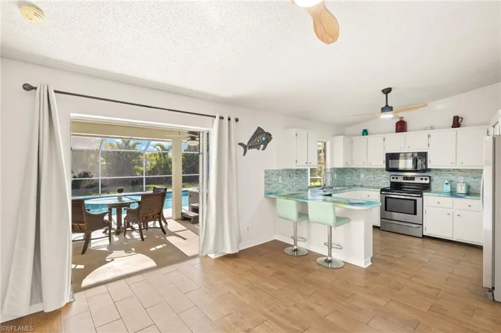 Kitchen featuring decorative backsplash, black microwave, ceiling fan, electric range, and a peninsula