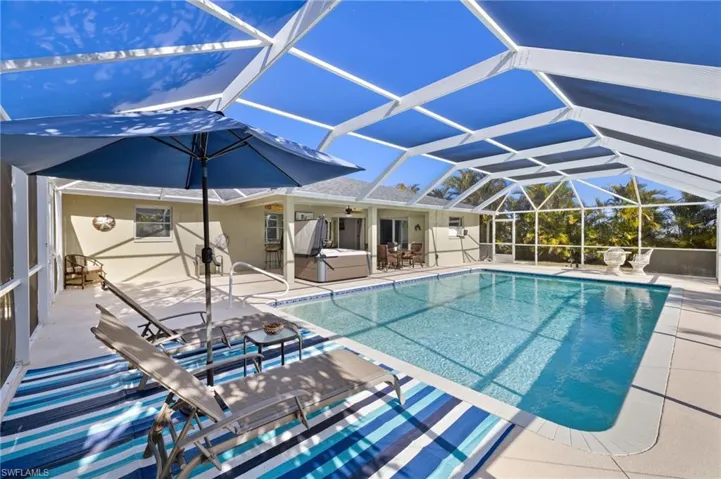 Pool with a hot tub, a patio area, glass enclosure, and a ceiling fan