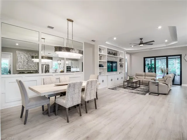 Dining area with light hardwood / wood-style flooring, plenty of natural light, ceiling fan, and a raised ceiling