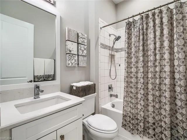 Full bathroom featuring vanity, shower / bath combo, and toilet