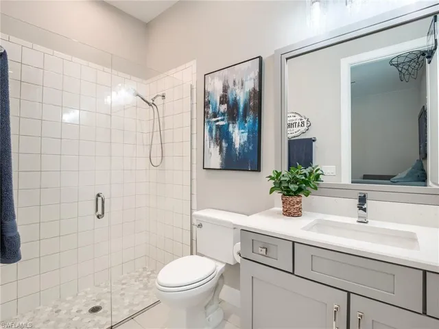 Bathroom with a shower with door, tile patterned floors, toilet, and vanity