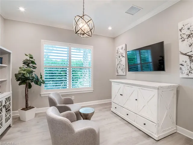 Living area with an inviting chandelier, crown molding, and light hardwood / wood-style floors