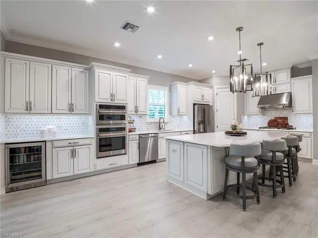 Kitchen with stainless steel appliances, decorative backsplash, a center island, wine cooler, and light hardwood / wood-style floors