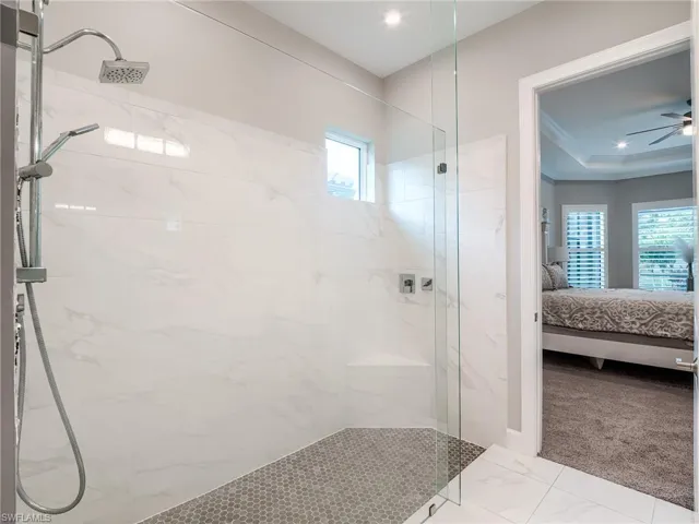 Bathroom with a tile shower, tile patterned floors, a wealth of natural light, and ceiling fan