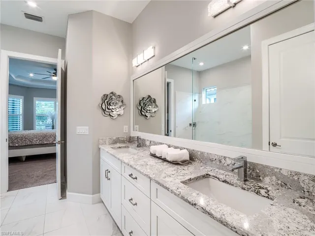 Bathroom with ceiling fan, tile patterned floors, and double sink vanity