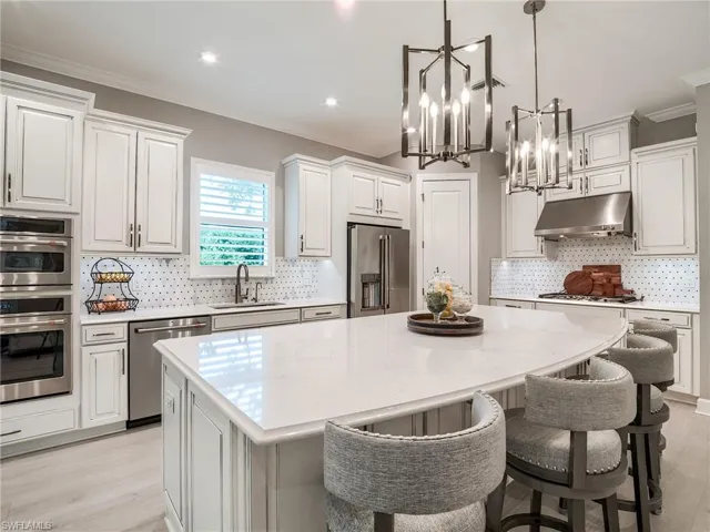 Kitchen featuring decorative light fixtures, sink, a center island, appliances with stainless steel finishes, and light hardwood / wood-style flooring