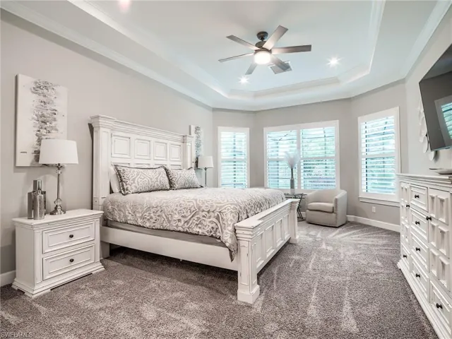 Bedroom with ceiling fan, crown molding, carpet floors, and a tray ceiling