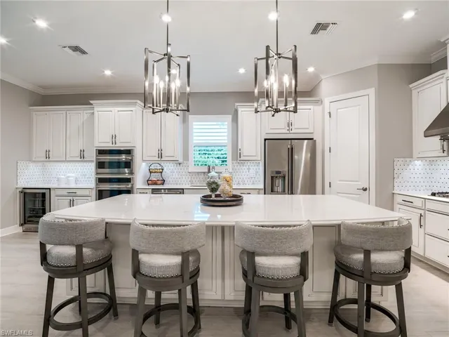 Kitchen featuring pendant lighting, decorative backsplash, a large island, and stainless steel appliances