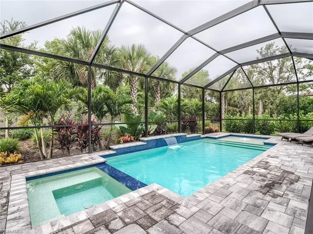 View of swimming pool with a patio area, an in ground hot tub, pool water feature, and a lanai
