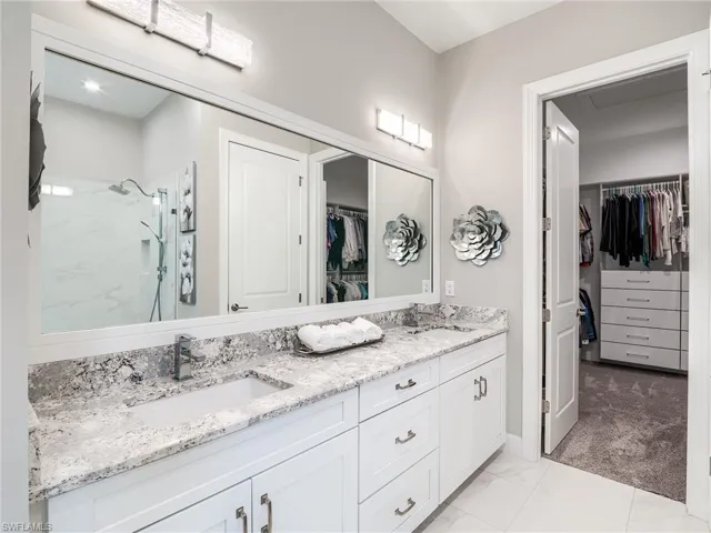 Bathroom featuring a shower, dual bowl vanity, and tile patterned floors