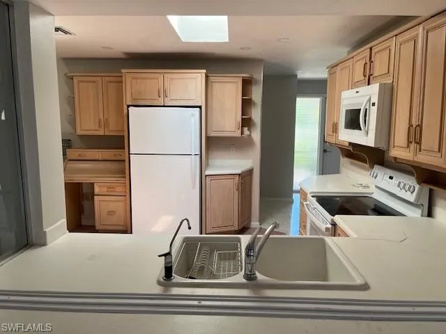 Kitchen featuring open shelves, white appliances, light countertops, and a skylight