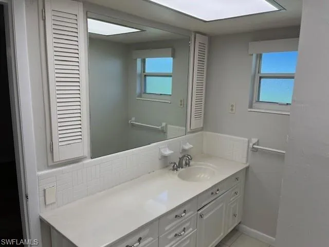 Bathroom featuring vanity, backsplash, healthy amount of natural light, and light tile patterned flooring
