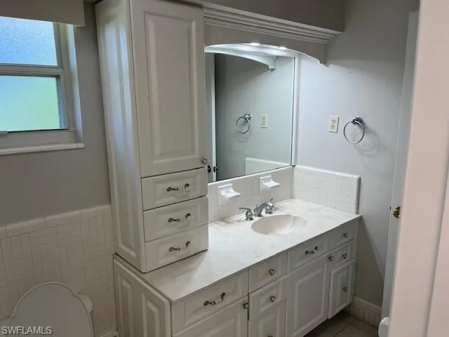 Half bath with vanity, tile walls, and light tile patterned flooring