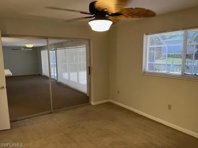 Unfurnished bedroom with light colored carpet, a ceiling fan, and access to exterior