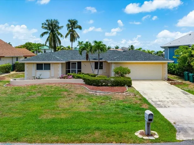 Single story home with a garage, driveway, a shingled roof, and a front lawn