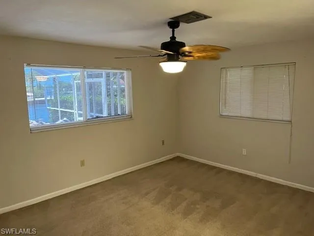 Carpeted empty room featuring baseboards and ceiling fan