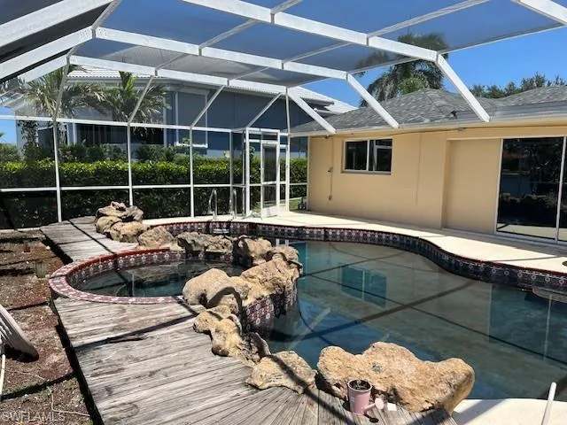 Swimming pool featuring a lanai, an in-ground hot tub, a patio area, and a sunroom