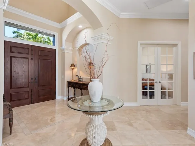 Foyer entrance with crown molding, arched walkways, baseboards, and french doors
