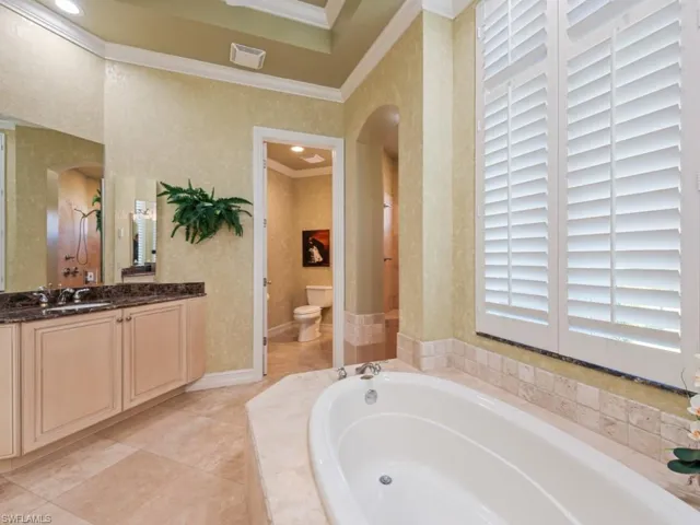 Bathroom with wallpapered walls, crown molding, toilet, a bath, and vanity