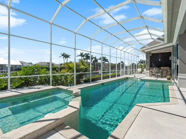 View of pool with ceiling fan, a pool with connected hot tub, a lanai, and a patio area