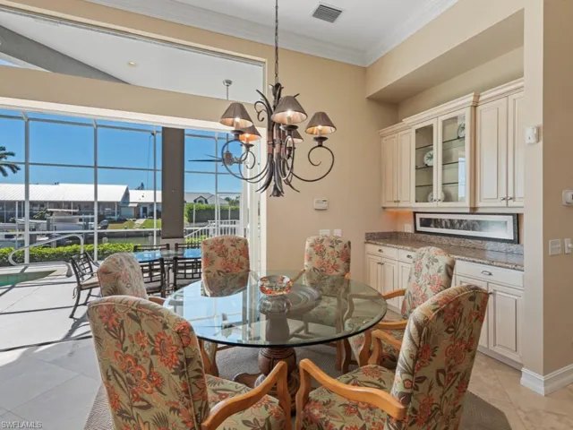 Dining area with an inviting chandelier, crown molding, light tile patterned floors, and visible vents