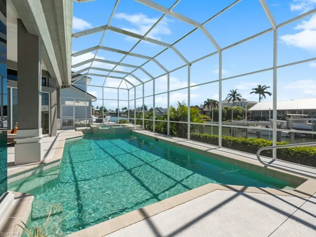 View of pool with glass enclosure, a patio, and a pool with connected hot tub