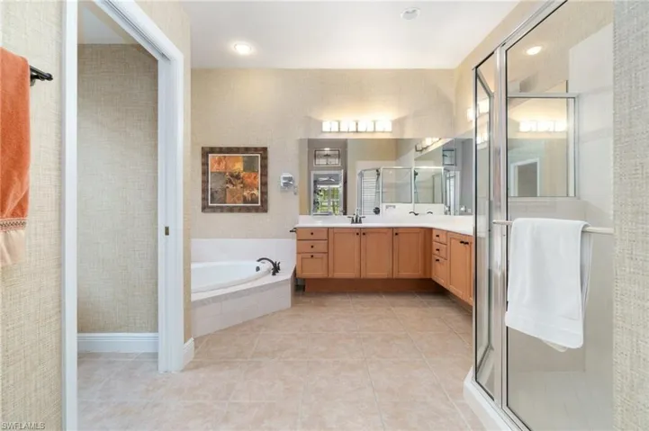 Bathroom featuring a bath, a stall shower, vanity, and tile patterned floors