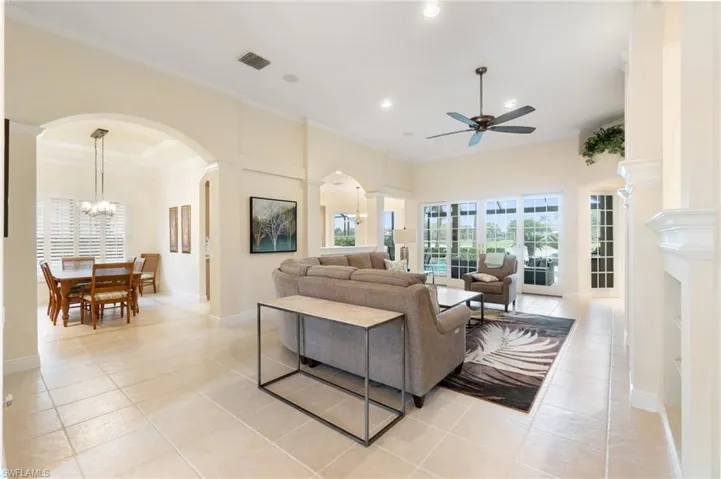Living room featuring arched walkways, ornamental molding, light tile patterned flooring, and visible vents