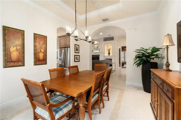 Dining space with visible vents, arched walkways, a chandelier, and crown molding