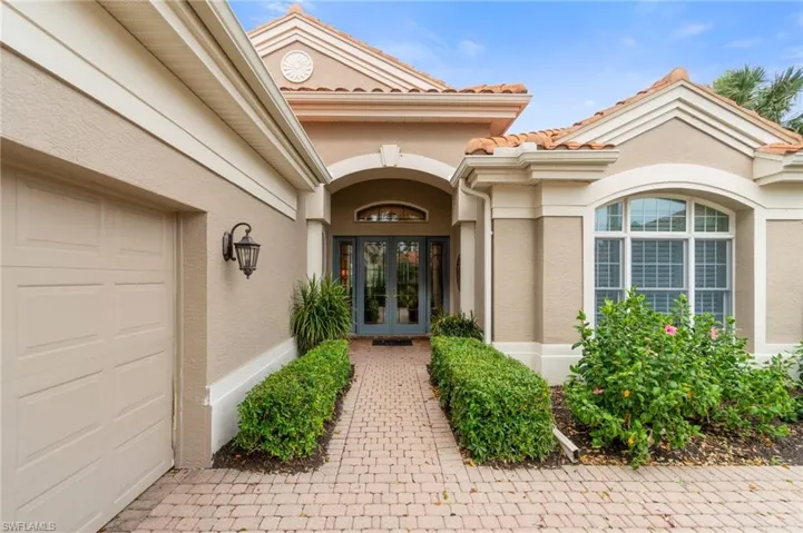 Property entrance with a garage, french doors, a tile roof, and stucco siding