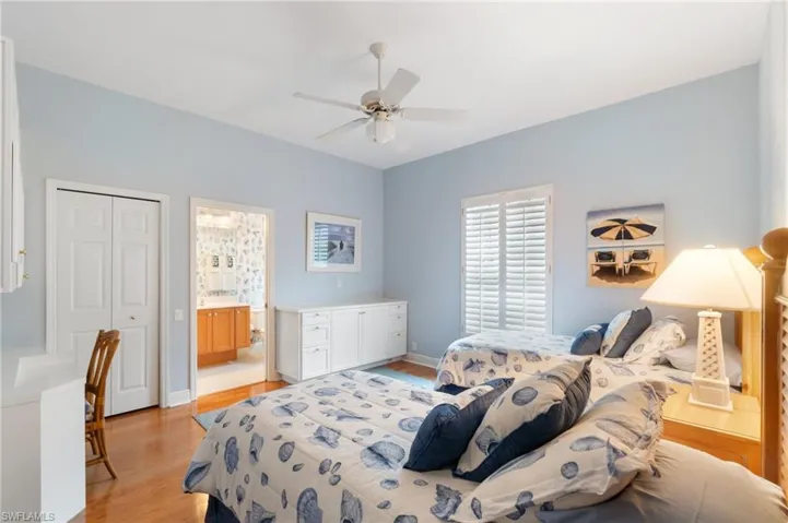 Bedroom featuring a closet, baseboards, light wood-style flooring, and ensuite bath