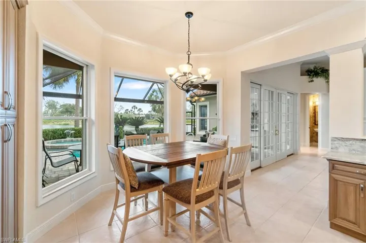Dining area with french doors, light tile patterned floors, an inviting chandelier, ornamental molding, and baseboards