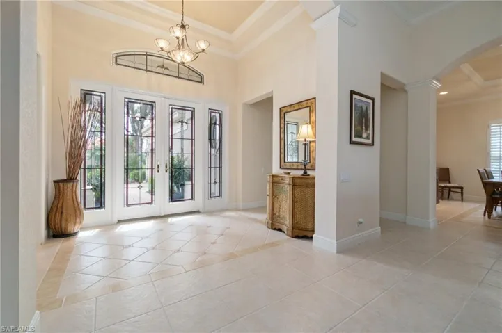 Foyer featuring arched walkways, light tile patterned floors, baseboards, ornamental molding, and decorative columns