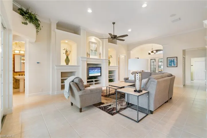 Living room featuring baseboards, recessed lighting, a fireplace, and crown molding