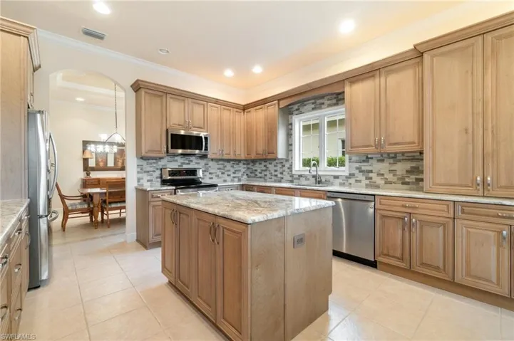 Kitchen with tasteful backsplash, visible vents, a kitchen island, ornamental molding, and stainless steel appliances