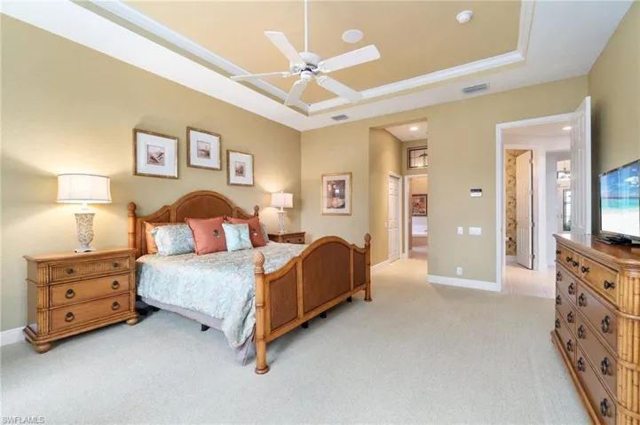 Bedroom with light carpet, visible vents, baseboards, and a raised ceiling