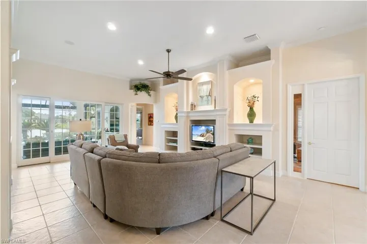 Living room featuring light tile patterned floors, recessed lighting, ornamental molding, a glass covered fireplace, and ceiling fan