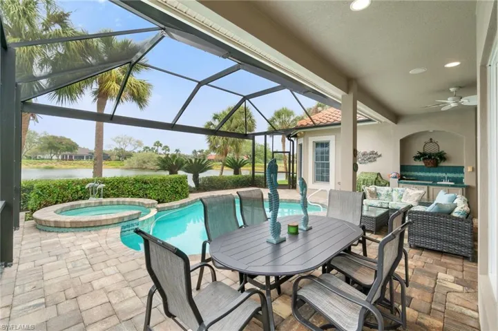 View of patio with a lanai, an outdoor hangout area, a water view, a pool with connected hot tub, and a ceiling fan