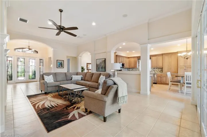 Living area with visible vents, arched walkways, crown molding, and light tile patterned flooring