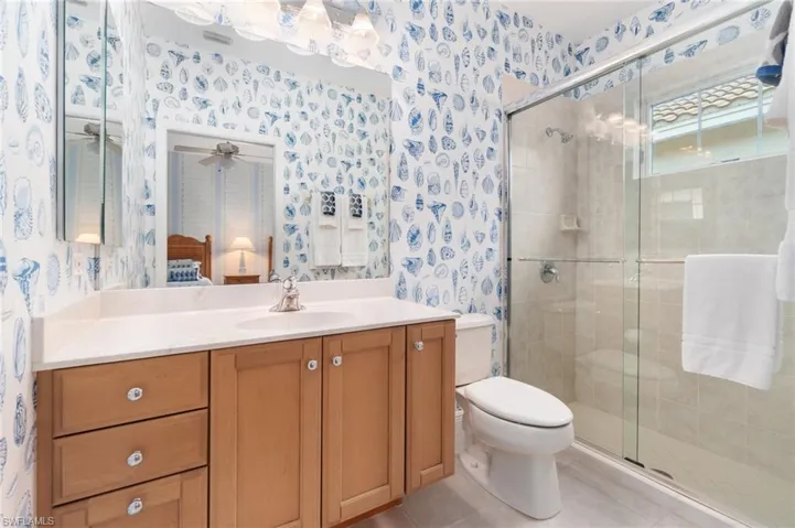 Full bath featuring a stall shower, toilet, and wallpapered walls